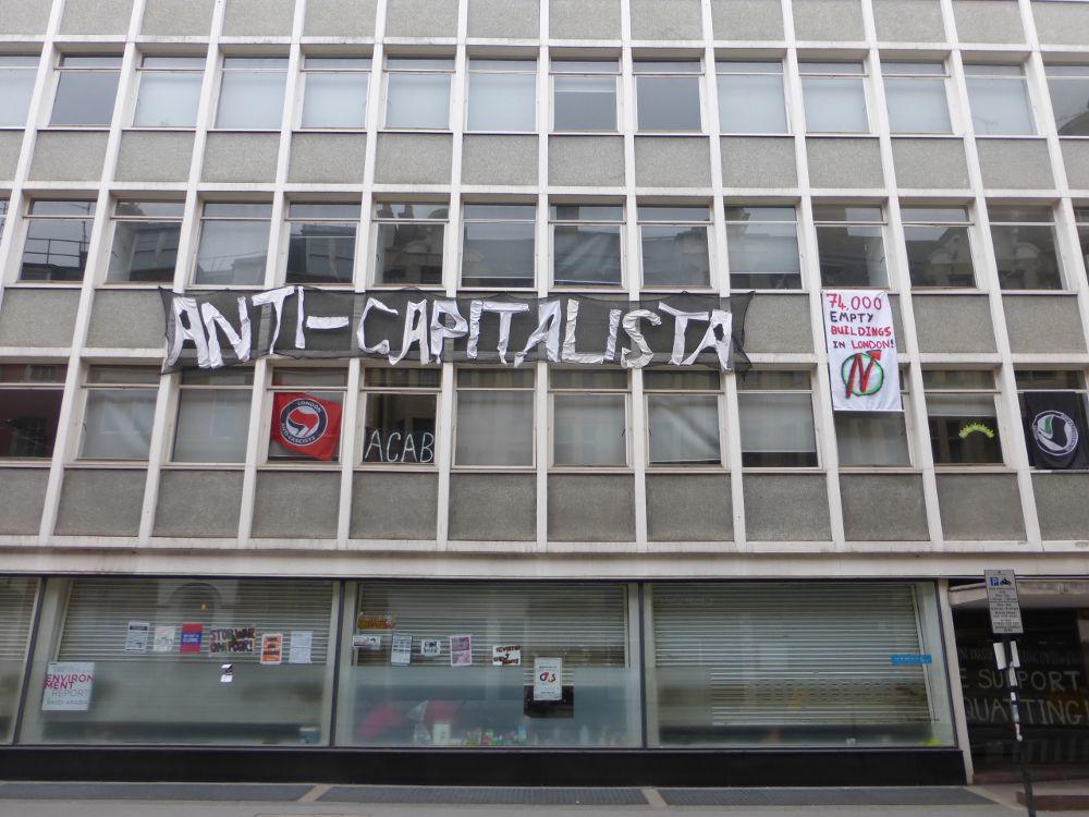 Front of building with anti-capitalist banner.